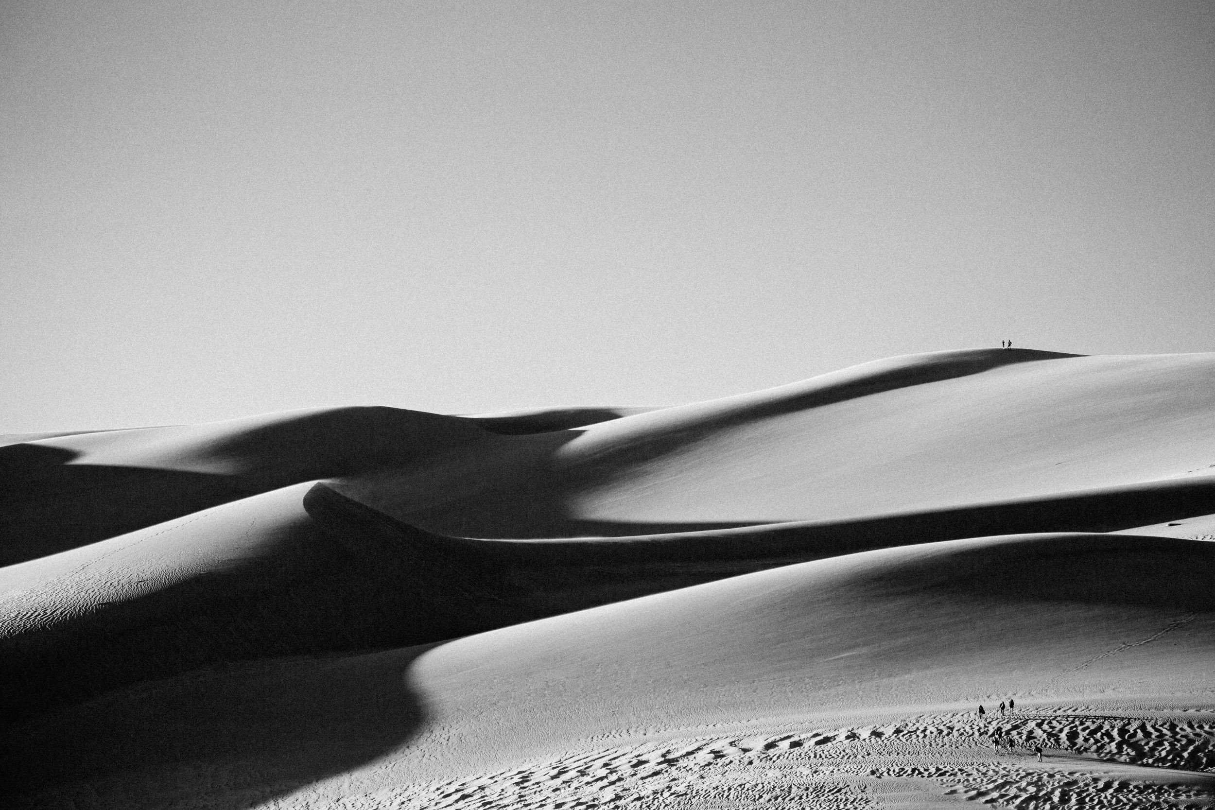 Hikers ascend sand dunes