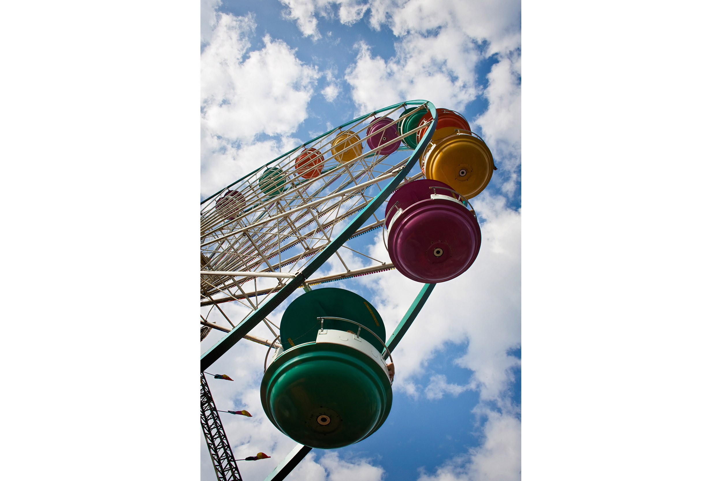 A multi-colored carousel rotates against the carnival’s blue sky