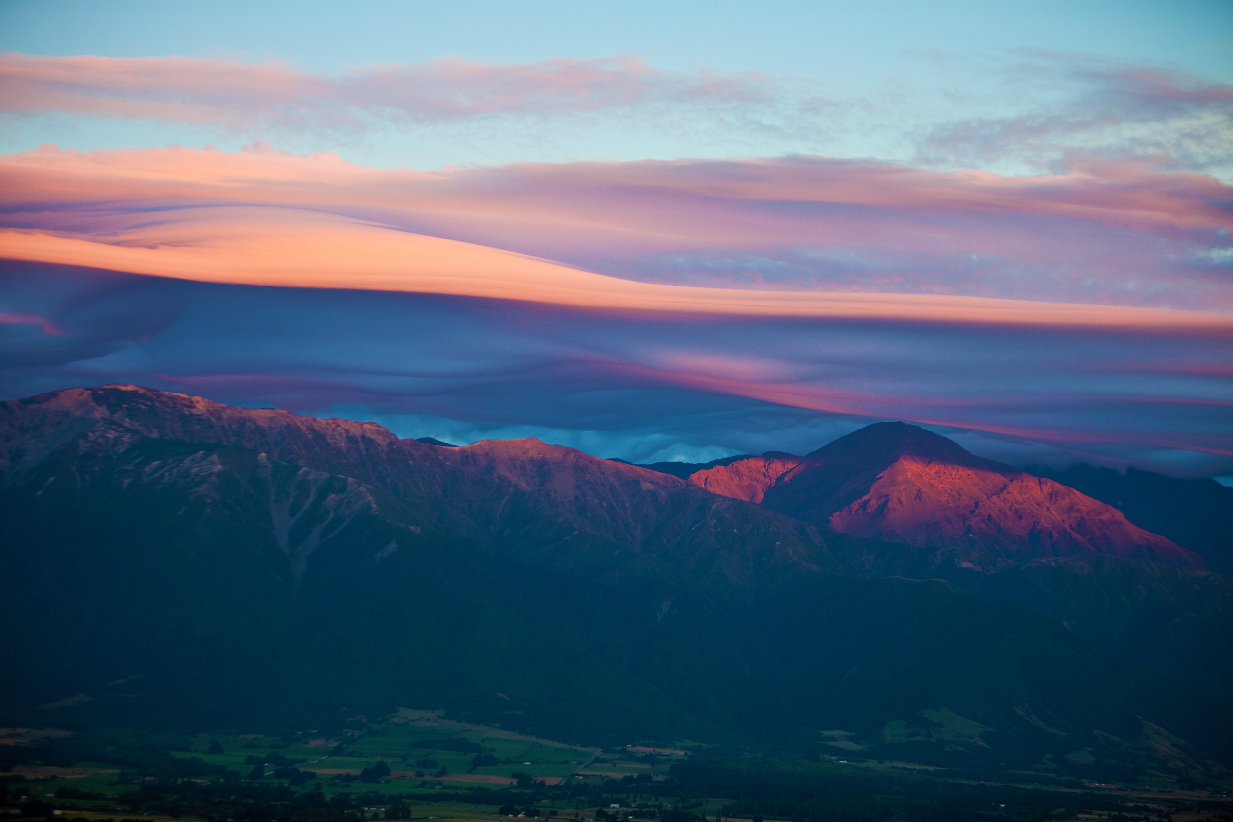 Sunrises forces its way through distant clouds to warm the chilly New Zealand mountain range