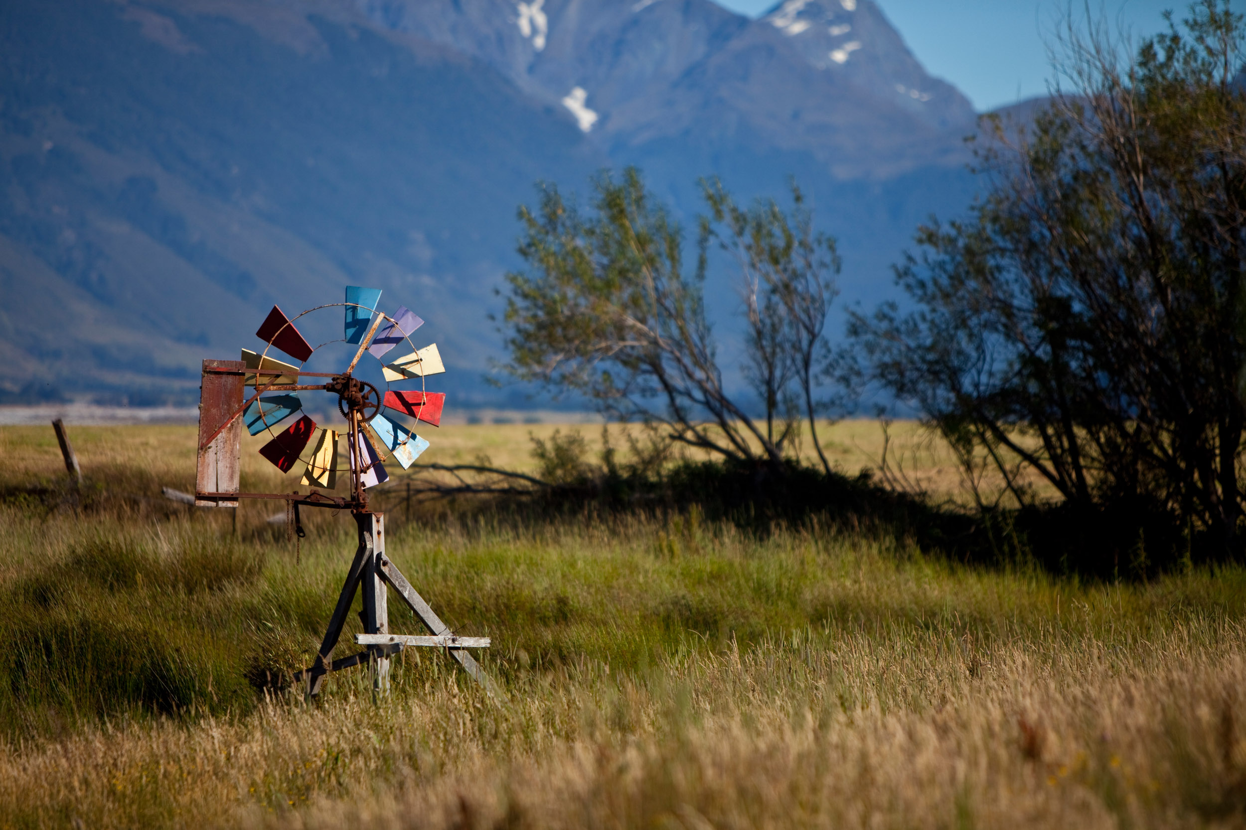A multi-colored windmill waits for the wind against a mountainous backdrop in New Zealand’s south island