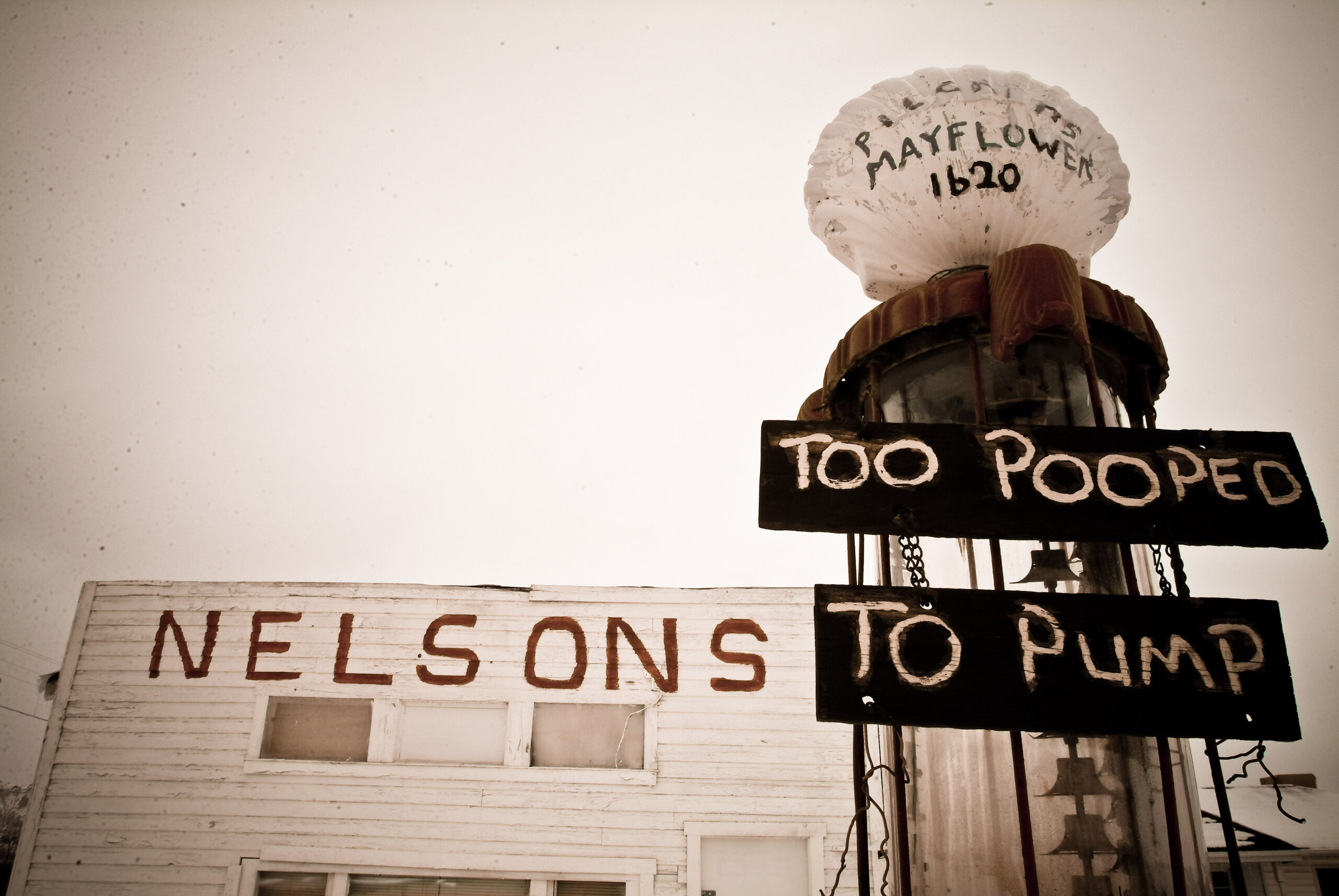 An abandoned gas station displays its operator's feelings, "Too pooped to pump"